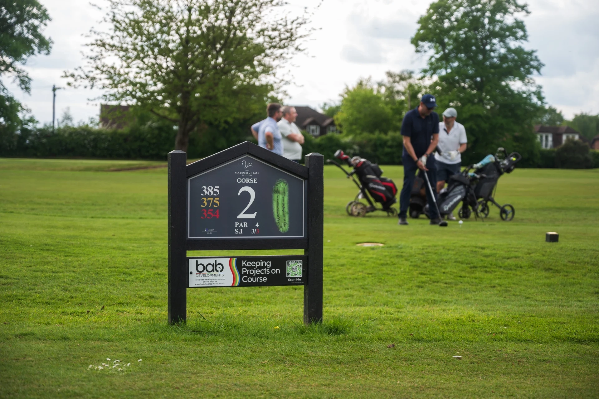 Golfers enjoying a round behind the second tee sign at Flackwell Heath Golf Club