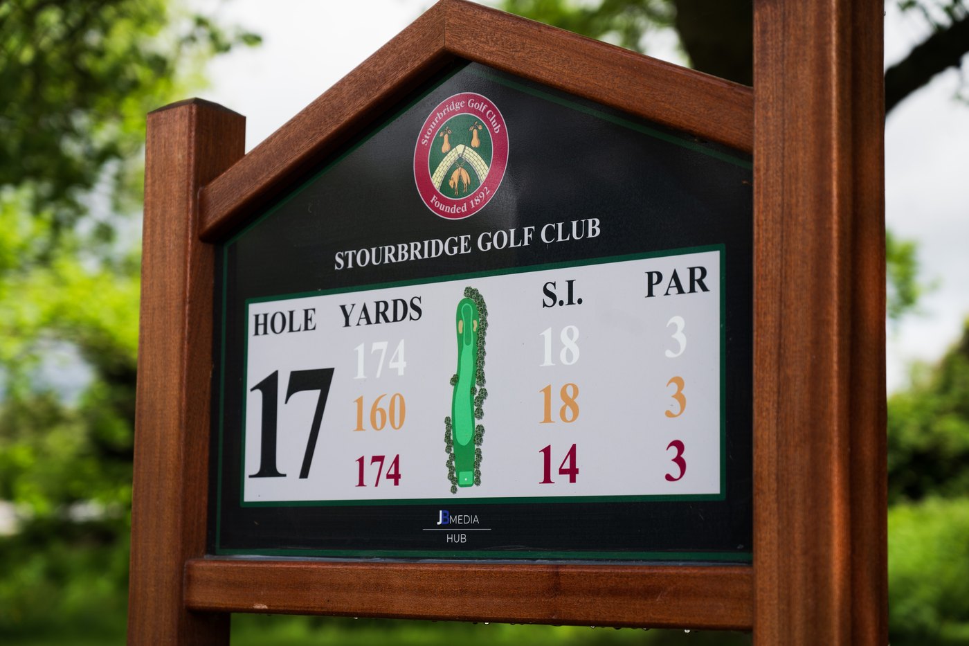 A JB Pro Panel Hardwood tee sign at Stourbridge Golf Club: a polished mahogany frame, its grain and warmth clearly visible, around a dark green yardage board